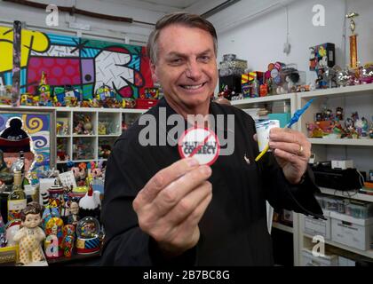 Der brasilianische Präsident Jair Bolsonaro lächelt, während er einen humorvollen Knopf während eines Besuchs im Kunststudio von Romero Britto 8. März 2020 in Miami, Florida, hält. Stockfoto