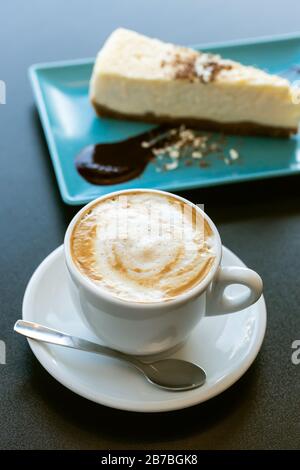 Käsekuchen und Cappuccino-Kaffee auf dem Tisch Stockfoto