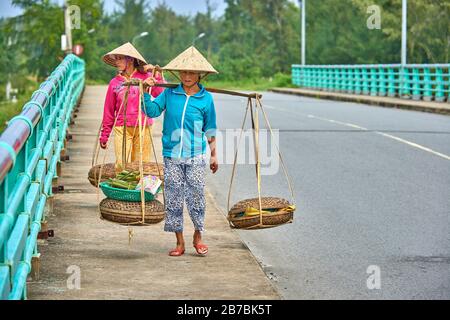 HOI AN, Vietnam-04 Dezember 2014:Unidentifizierter Anbieter in Hoi an City.vietnamesische Händler mit tropischem Obst und Gemüse beladenem Korb auf dem Fahrrad. Leben Stockfoto