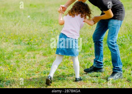 Mann ergriff Mädchen an den Armen und zieht. Vater spielt mit Tochter. Das Tageskonzept des Vaters. Stockfoto