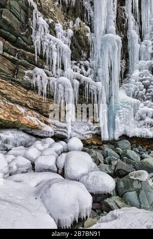 Gefrorene Seeps bilden Eiszapfen und Wasserfälle entlang der felsigen Klippen von Herring Cove, in der Nähe von Champneys West in Neufundland, Kanada Stockfoto