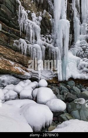 Gefrorene Seeps bilden Eiszapfen und Wasserfälle entlang der felsigen Klippen von Herring Cove, in der Nähe von Champneys West in Neufundland, Kanada Stockfoto