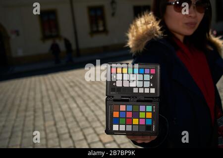 Frau, die den X-Rite Colorchecker Pass an Ort und Stelle hält, um den Weißabgleich der Kamera und ein Farbkalibrierungsfoto zu erhalten Stockfoto