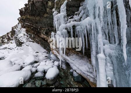 Gefrorene Seeps bilden Eiszapfen und Wasserfälle entlang der felsigen Klippen von Herring Cove, in der Nähe von Champneys West in Neufundland, Kanada Stockfoto