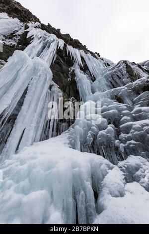 Gefrorene Seeps bilden Eiszapfen und Wasserfälle entlang der felsigen Klippen von Herring Cove, in der Nähe von Champneys West in Neufundland, Kanada Stockfoto