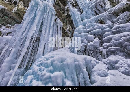 Gefrorene Seeps bilden Eiszapfen und Wasserfälle entlang der felsigen Klippen von Herring Cove, in der Nähe von Champneys West in Neufundland, Kanada Stockfoto