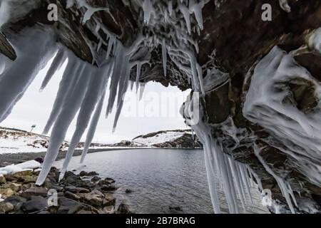 Gefrorene Seeps bilden Eiszapfen und Wasserfälle entlang der felsigen Klippen von Herring Cove, in der Nähe von Champneys West in Neufundland, Kanada Stockfoto