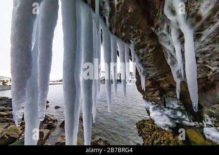 Gefrorene Seeps bilden Eiszapfen und Wasserfälle entlang der felsigen Klippen von Herring Cove, in der Nähe von Champneys West in Neufundland, Kanada Stockfoto