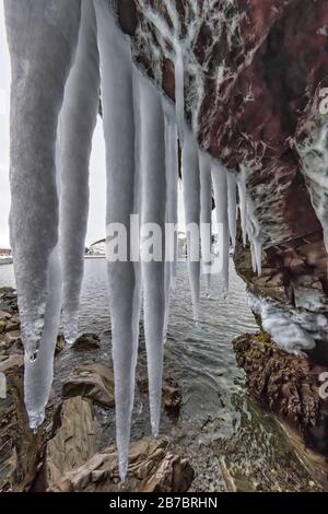 Gefrorene Seeps bilden Eiszapfen und Wasserfälle entlang der felsigen Klippen von Herring Cove, in der Nähe von Champneys West in Neufundland, Kanada Stockfoto