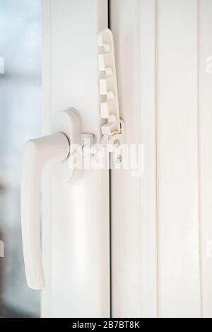 Geschlossenes weißes PVC-Fenster mit angebrachtem Befestigungselement für die Belüftung. Nahaufnahme. Stockfoto