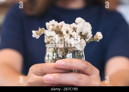 Eine Frau, die innen eine Vase mit weißen Blumen hält Stockfoto
