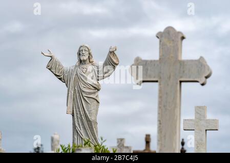 Marmor-Kruzifixe und eine lebensgroße Jesusfigur auf einem Friedhof geben ein Christenthema vor Stockfoto