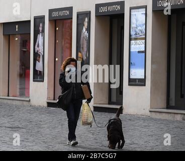 Berlin, 12. März. März 2020. Eine Frau, die eine Gesichtsmaske trägt, läuft am 12. März 2020 einen Hund auf der Einkaufsstraße Via dei Condotti in Rom, Italien. UM MIT XINHUA SCHLAGZEILEN VOM 15. MÄRZ 2020 ZU GEHEN. Credit: Elisa Lingria/Xinhua/Alamy Live News Stockfoto