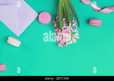 Flache Feder-Laienzusammensetzung mit Makronen und rosafarbenen Hyazinthblüten Stockfoto