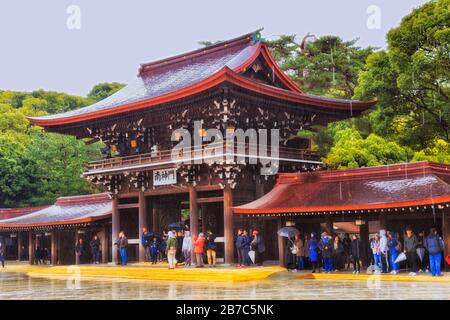 Tokio, Japan - 31. Dezember 2020: Der imperiale Garten und der Buiddhismus-Tempelkomplex Meiji-jingu. Eingangstor um den Innenhof bei Regen mit Touristen hidi Stockfoto