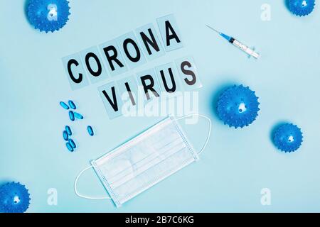 Abstraktes Virusstrain-Modell der Coronavirus-Krankheit COVID-19, Pillen, Spritze und Maske auf blau Stockfoto