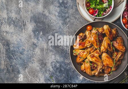 Geröstete bbq-Flügel mit grünem Salat mit Tomaten. Draufsicht. Stockfoto