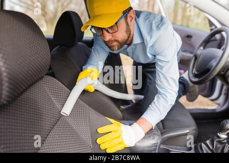 Mann Arbeiter mit Staubsauger im Auto Stockfoto
