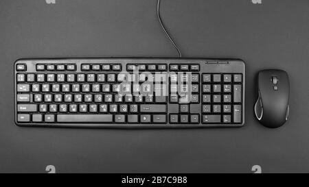 Tastatur für Computer mit einem Kabel auf dem Tisch. In der Nähe liegt eine kabellose Maus. Moderne Bürogeräte Stockfoto
