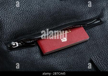 Der Pass sieht aus der Tasche einer schwarzen Ledertasche aus, die aus der Nähe, aus handgefertigten, natürlichen Materialien besteht. Stockfoto