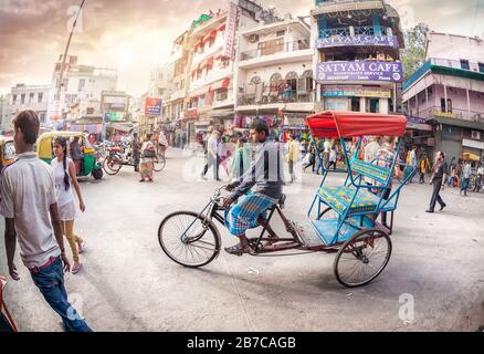 NEU-DELHI, INDIEN - 23. FEBRUAR 2015: Rikschah-Fahrer auf überfüllter Straße mit Geschäften, Hotels, Transport und Leuten in Main Bazaar, Paharganj Stockfoto