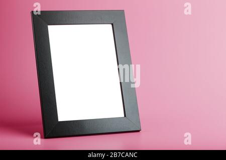 Schwarzer Bilderrahmen mit leerem Raum auf pinkfarbenem Hintergrund. Stockfoto
