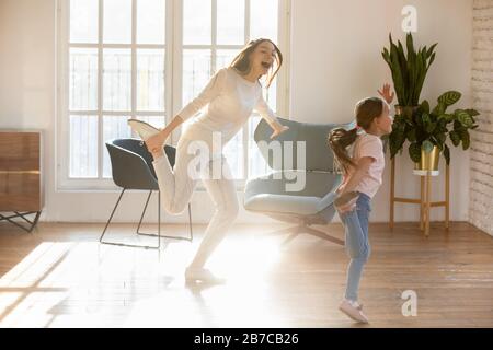 Aufgeregtes kleines Vorschulmädchen, das mit freudiger Mutter tanzt. Stockfoto