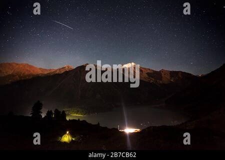 Sternenschießen am Nachthimmel im Berglager in der Nähe des großen Almaty-Sees in Kasachstan Stockfoto