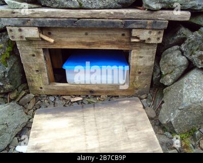 Holzkiste & Buch im Steinhaus auf dem Gipfel des schottischen Bergkorbboss 'Morven' in der Nähe von Ballater, Deeside, Schottland, Stockfoto