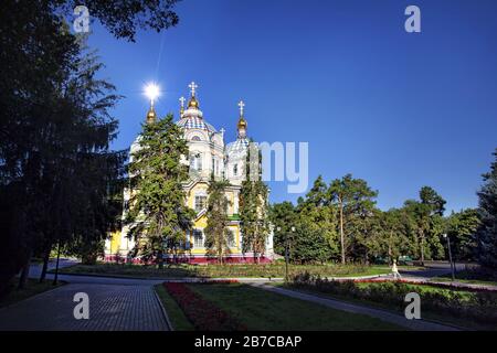 Frau in weißem Kleid und Gelb in die berühmte orthodoxe Kirche in Almaty, Kasachstan Stockfoto