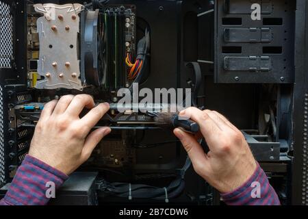 Der Mensch reinigt den Staub von der Computerhardware Stockfoto