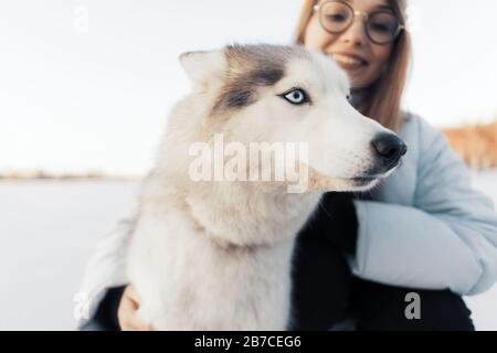 Glückliche junge Mädchen spielen mit sibirischen Husky Hund in Winter Park. Sie gehen auf einem zugefrorenen See Stockfoto