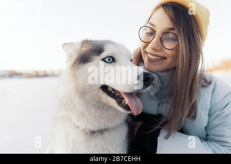 Glückliche junge Mädchen spielen mit sibirischen Husky Hund in Winter Park. Sie gehen auf einem zugefrorenen See Stockfoto