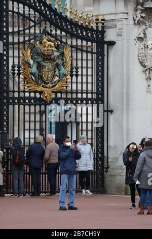 Ein Tourist, der eine Gesichtsmaske trägt, um sich vor der Ausbreitung von Coronavirus zu schützen, trifft eine selfie außerhalb des Buckingham Palace, London, wie Gesundheitsminister Matt Hancock sagte, dass die Minister noch keine Entscheidung treffen müssen, ob Versammlungen von über 500 Personen im Rest des Vereinigten Königreichs verboten werden sollen. Nachdem Schottland sagte, dass es ab Montag Einschränkungen bringen würde. Stockfoto