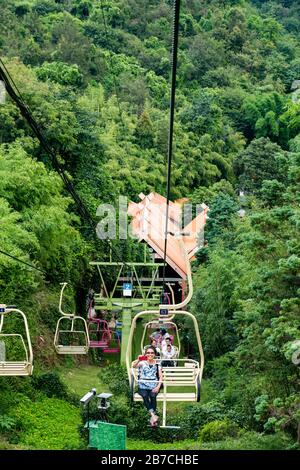 Touristen fahren mit der Seilbahn zum Gipfel im Jiuxiang Gorge and Cave National Park in Jiuxiang Yi und Hui Autonomous District, Yiliang County, China. Stockfoto