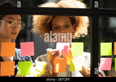 Der afroamerikanische Mentor erklärt dem Mitarbeiter die Strategie auf Haftpapieren Stockfoto