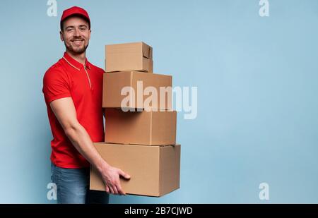 Courier hat viele Schachteln zur Lieferung. Emotionaler Ausdruck. Hintergrund Zyan Stockfoto