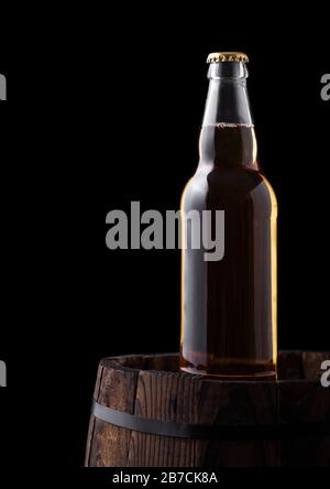 Kalte Flasche Handwerk Bier auf alten Holzfass auf schwarzem Hintergrund Stockfoto