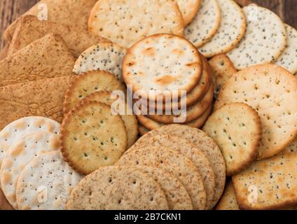 Verschiedene Biokrispige Weizen-, Roggen- und Mais-Fladenbrot-Cracker mit Sesam und Salz in runder Platte auf Holzhintergrund. Stockfoto