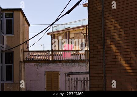 Ein rosafarbenes Badetuch, das an einem Draht mit Wäscheklappen auf dem Balkon eines ländlichen Hauses hängt (Pesaro, Italien, Europa) Stockfoto