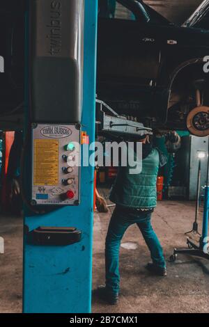 Lemberg, Ukraine - 03. März 2020: Der Mechaniker hob das Auto mit einem Aufzug an, um den Motor 2020 zu warten Stockfoto