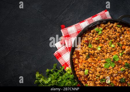 Bolognese steht in Eisenplatte am schwarzen Tisch. Stockfoto