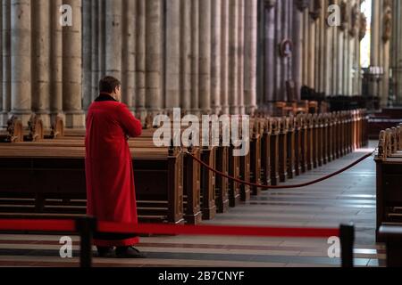 Köln, Deutschland. März 2020. Ein Domschweizer steht im leeren Kölner Dom zwischen den Bänken. Der Dom ist ab Sonntag nur noch für Menschen geöffnet, die ihn zum Beten besuchen wollen. Gottesdienste werden in der Kamera gefeiert und von Domradio.de ausgestrahlt. Achtung: Nur im Zusammenhang mit der Berichterstattung über die Maßnahmen des Kölner Doms in der aktuellen Corona-Epidemie verwenden. Credit: Marius Becker / dpa / Alamy Live News Stockfoto