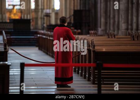 Köln, Deutschland. März 2020. Ein Domschweizer steht im leeren Kölner Dom zwischen den Bänken. Der Dom ist ab Sonntag nur noch für Menschen geöffnet, die ihn zum Beten besuchen wollen. Gottesdienste werden in der Kamera gefeiert und von Domradio.de ausgestrahlt. Achtung: Nur im Zusammenhang mit der Berichterstattung über die Maßnahmen des Kölner Doms in der aktuellen Corona-Epidemie verwenden. Credit: Marius Becker / dpa / Alamy Live News Stockfoto