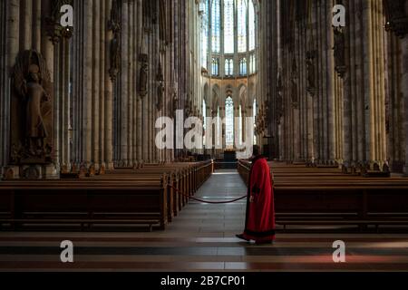 Köln, Deutschland. März 2020. Ein Domschweizer steht im leeren Kölner Dom zwischen den Bänken. Der Dom ist ab Sonntag nur noch für Menschen geöffnet, die ihn zum Beten besuchen wollen. Gottesdienste werden in der Kamera gefeiert und von Domradio.de ausgestrahlt. Achtung: Nur im Zusammenhang mit der Berichterstattung über die Maßnahmen des Kölner Doms in der aktuellen Corona-Epidemie verwenden. Credit: Marius Becker / dpa / Alamy Live News Stockfoto