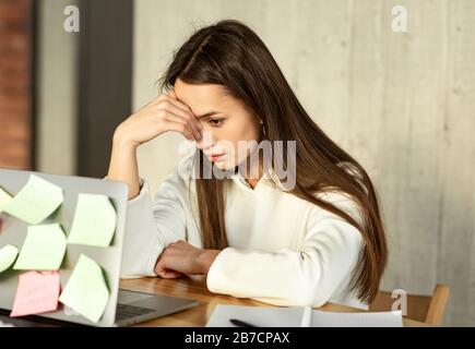 Multitasking freiberufliche Konzepte. Müdes Mädchen hält den Kopf Stockfoto