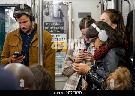 Junge Leute stehen und benutzen Smartphones in der pariser Metro, Paris, Frankreich, Europa Stockfoto