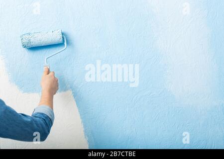 Färbt die Texturwand mit der Walze blau Stockfoto