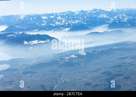 Einzigartiges alpines Luftpanorama. Blauer Planet Erde Höhenflug von einem Flugkabinenfenster aus, das über Zürich fliegt, aus dem Blick auf die Schweizer Alpen Stockfoto