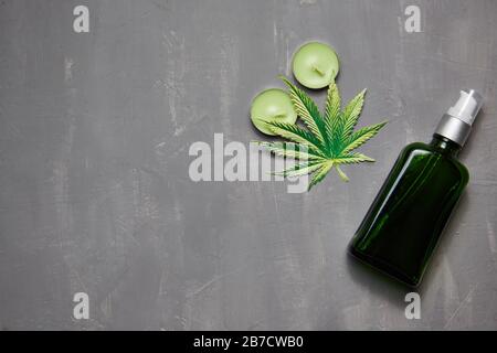 Cannabiskraut und Blätter zur Behandlung, Brühe, Tinktur, Extrakt, Öl. Flasche mit Öl, Kerzen Copyspace, Draufsicht Stockfoto